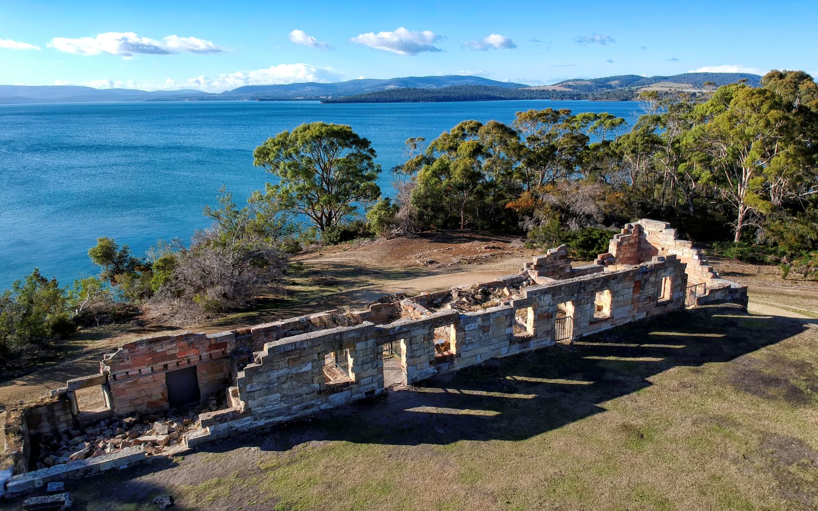 An old coal mine site located on the Tasman Peninsula showing the remains of sandstone buildings against a beautiful seaside backdrop